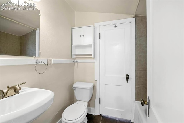 bathroom with vaulted ceiling, toilet, sink, and tile patterned floors