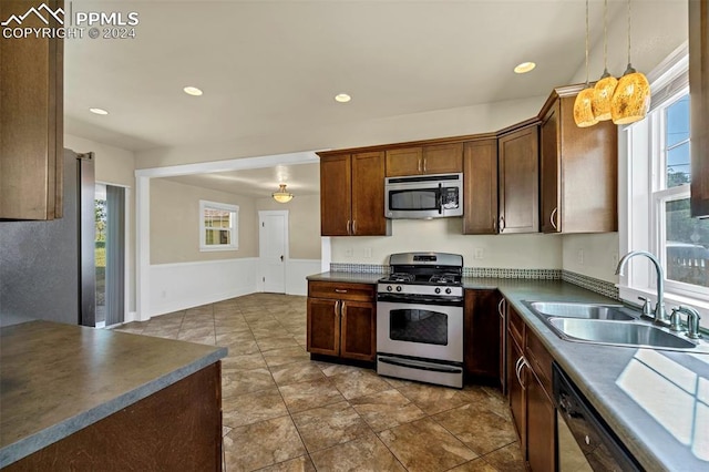 kitchen featuring decorative light fixtures, a wealth of natural light, stainless steel appliances, and sink