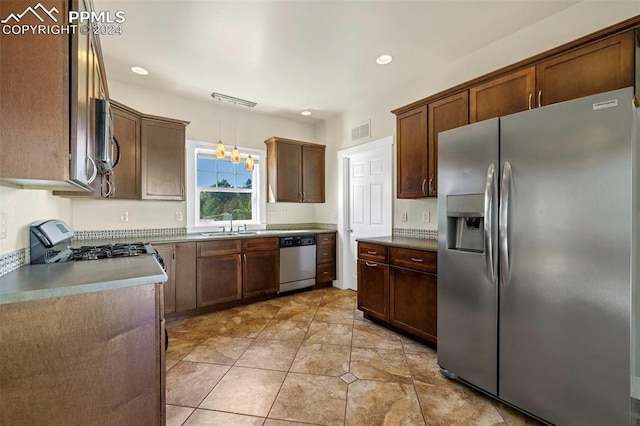 kitchen with hanging light fixtures, stainless steel appliances, sink, and light tile patterned floors