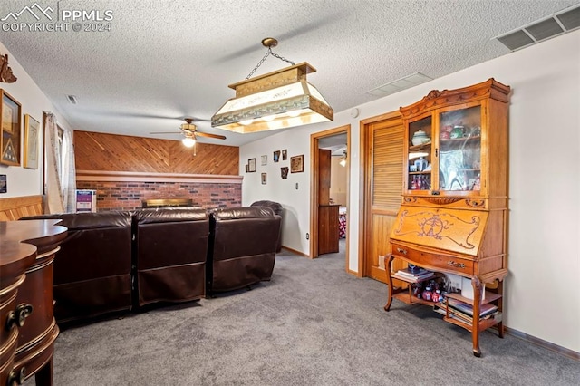 carpeted living room with a textured ceiling, wood walls, and ceiling fan