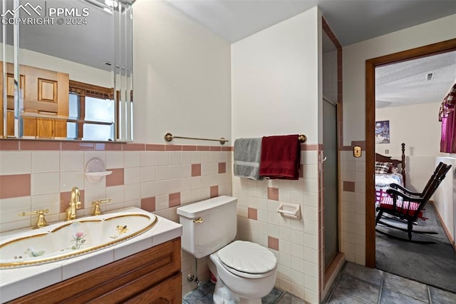 bathroom with tile walls, vanity, toilet, and an enclosed shower