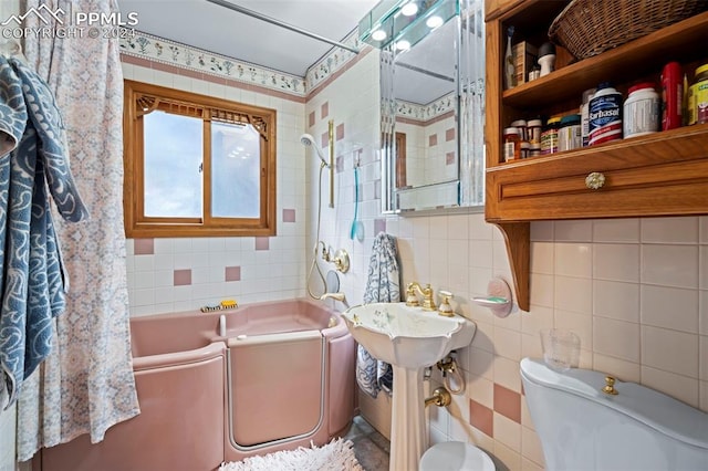 bathroom with tile walls, shower / bath combo with shower curtain, and toilet