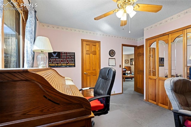 home office with ceiling fan, a textured ceiling, and light carpet