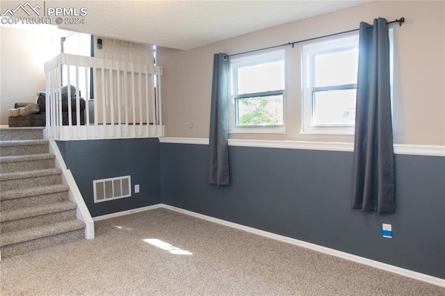 spare room featuring carpet flooring and a textured ceiling