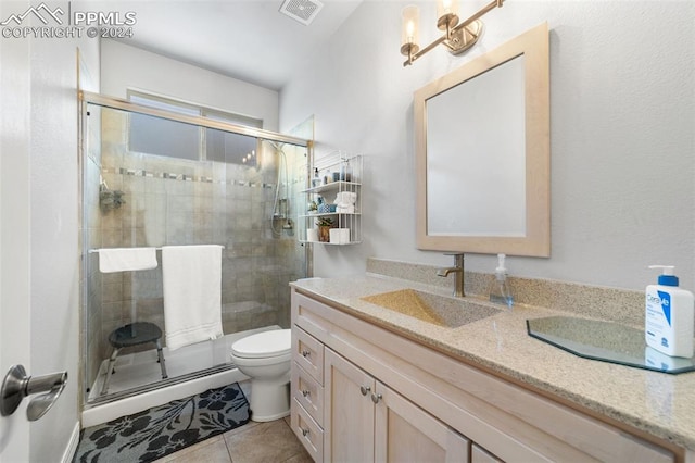 bathroom featuring vanity, a shower with shower door, toilet, and tile patterned floors