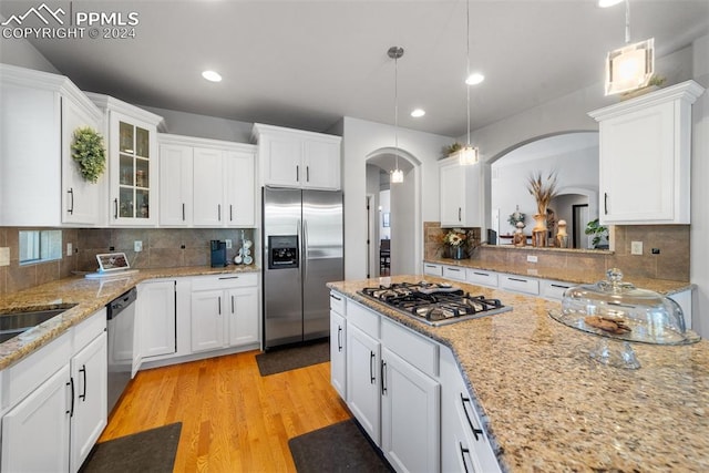 kitchen featuring light hardwood / wood-style flooring, white cabinets, appliances with stainless steel finishes, and hanging light fixtures