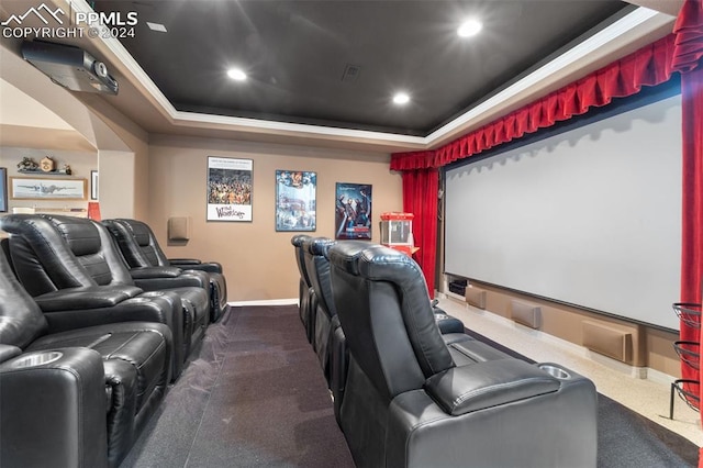 cinema room with dark carpet, a tray ceiling, and crown molding