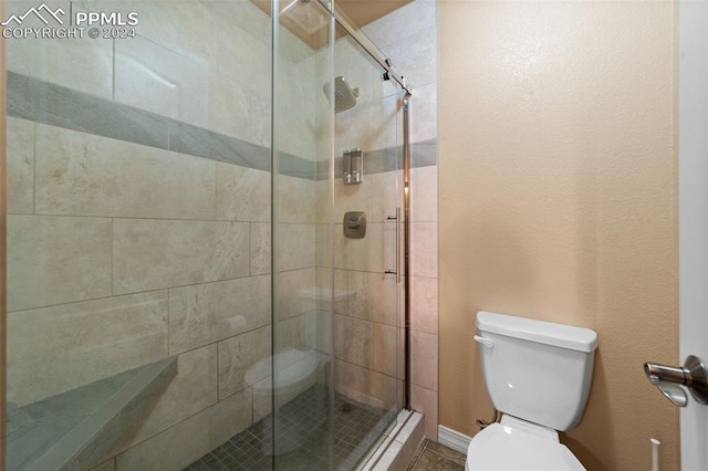 bathroom with a shower with shower door and toilet