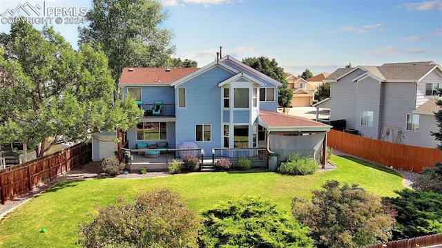 rear view of house featuring a balcony, a deck, and a yard