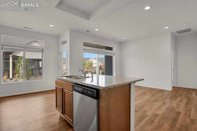 kitchen with light stone counters, sink, stainless steel dishwasher, a center island with sink, and light hardwood / wood-style floors