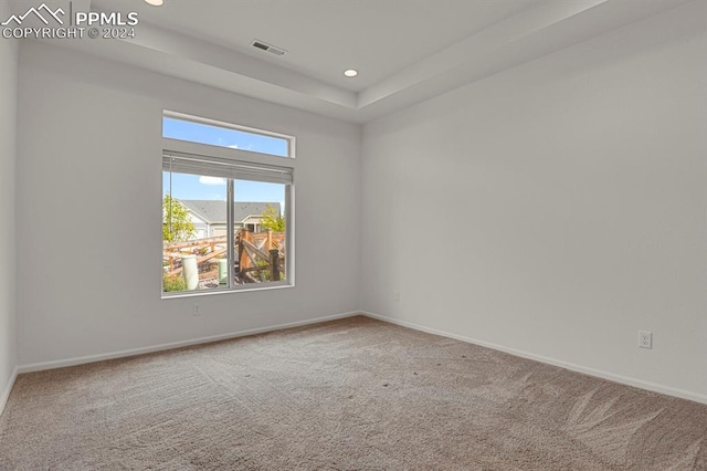 carpeted empty room featuring a tray ceiling