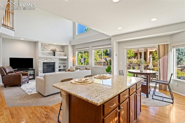 kitchen with light wood-type flooring, a fireplace, a towering ceiling, and a center island