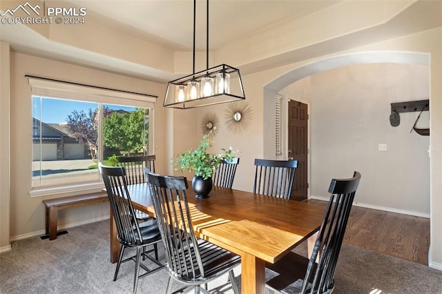 dining area with carpet floors, a notable chandelier, and a tray ceiling