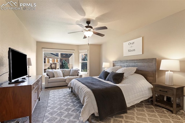 bedroom with ceiling fan, a textured ceiling, and light carpet