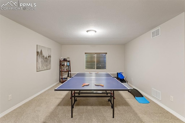 game room with a textured ceiling and light colored carpet