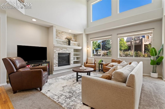 living room featuring built in shelves, a fireplace, a high ceiling, and wood-type flooring