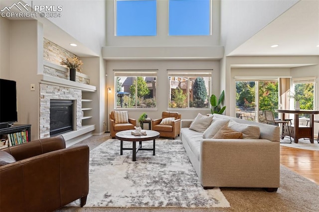 living room with a towering ceiling, a fireplace, and plenty of natural light