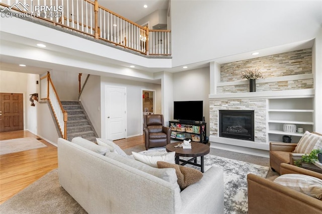 living room with wood-type flooring, a fireplace, built in features, and a high ceiling