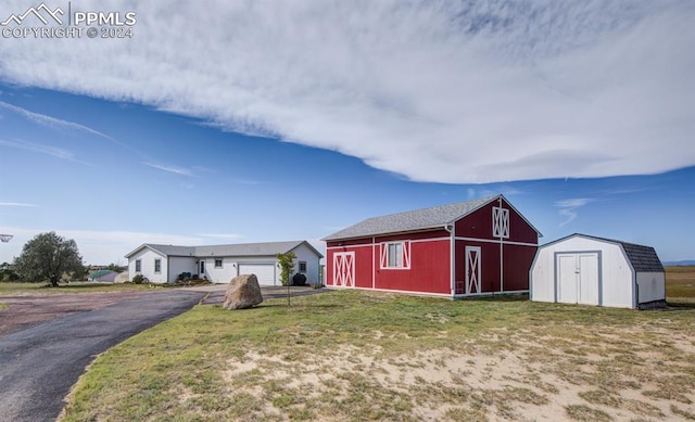 view of front of home with a storage shed, a garage, and a front yard