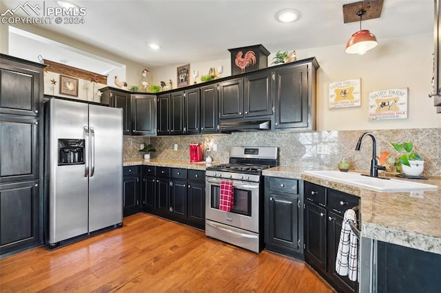 kitchen with pendant lighting, tasteful backsplash, sink, light hardwood / wood-style flooring, and stainless steel appliances