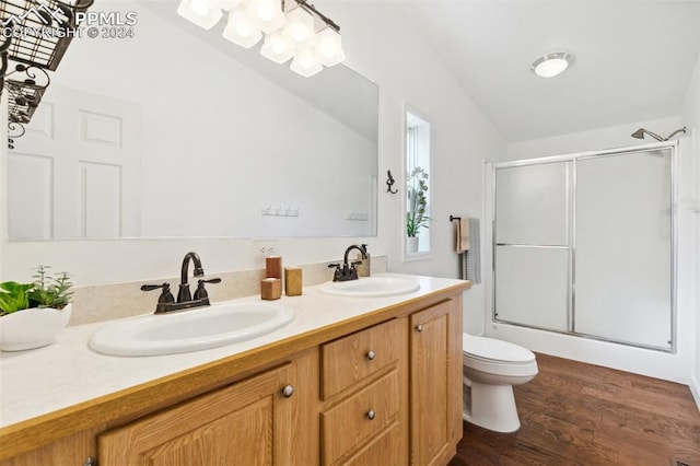 bathroom with hardwood / wood-style flooring, lofted ceiling, walk in shower, vanity, and toilet