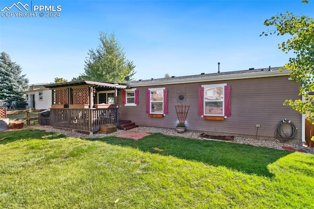 rear view of house with a deck and a yard