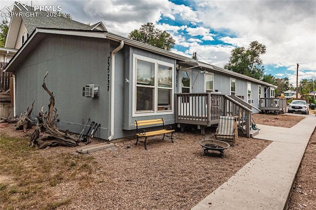 view of home's exterior with a deck and a fire pit