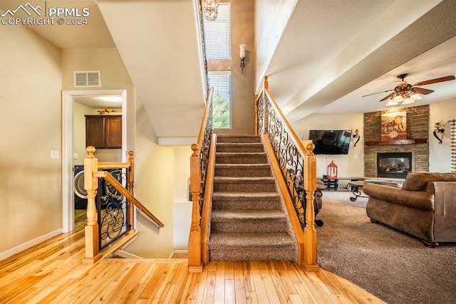 stairway featuring wood-type flooring, a fireplace, and ceiling fan