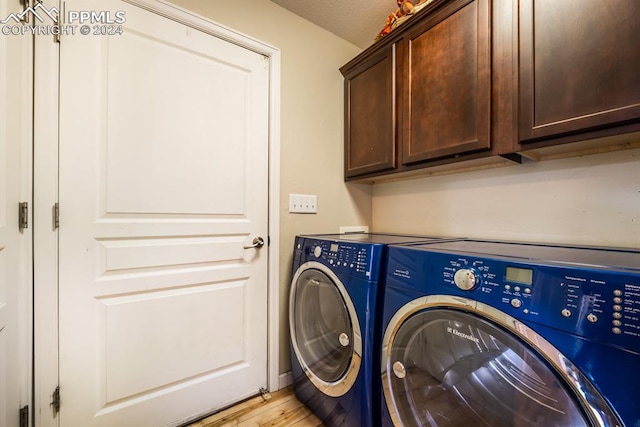 laundry area with separate washer and dryer, cabinets, and light hardwood / wood-style floors