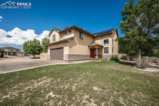 view of front of house featuring a garage, solar panels, and a front yard