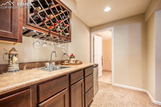 kitchen with light carpet, dark brown cabinets, stainless steel dishwasher, and sink