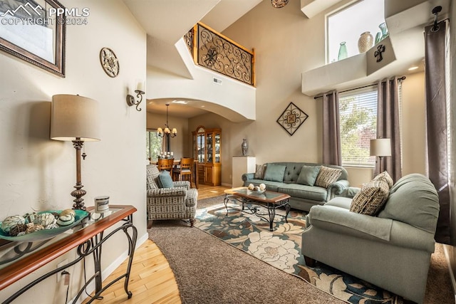 living room featuring an inviting chandelier, a high ceiling, and hardwood / wood-style flooring