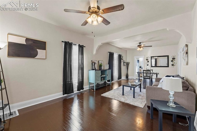 living room featuring ceiling fan and dark wood-type flooring