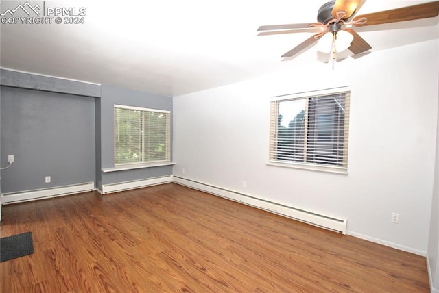 spare room featuring a baseboard heating unit, ceiling fan, and wood-type flooring