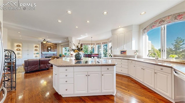 kitchen with a healthy amount of sunlight, white cabinetry, sink, and a brick fireplace