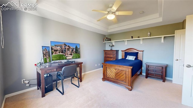 bedroom featuring ceiling fan, carpet floors, and a tray ceiling