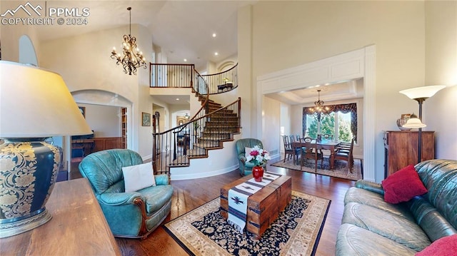 living room with an inviting chandelier, high vaulted ceiling, and dark hardwood / wood-style flooring