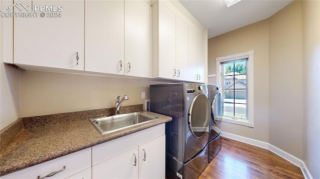 laundry room featuring cabinets, sink, washing machine and clothes dryer, and hardwood / wood-style flooring