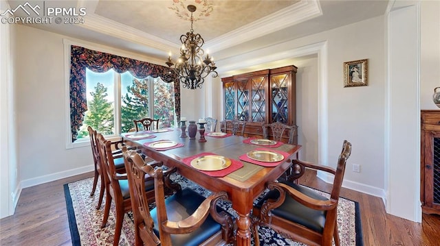 dining space featuring an inviting chandelier, a raised ceiling, crown molding, and dark hardwood / wood-style flooring