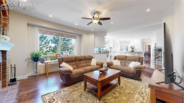 living room featuring ceiling fan, a brick fireplace, and hardwood / wood-style floors