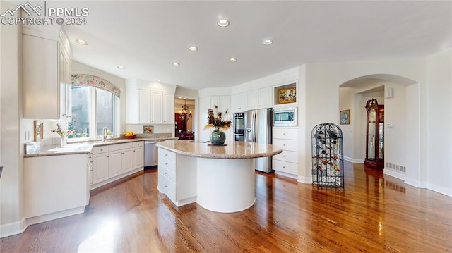 kitchen featuring sink, white cabinetry, appliances with stainless steel finishes, a center island, and hardwood / wood-style floors