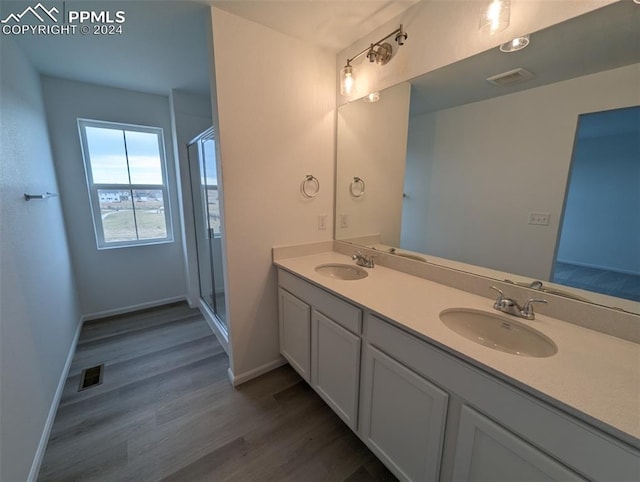 bathroom with hardwood / wood-style floors, vanity, and a shower with shower door