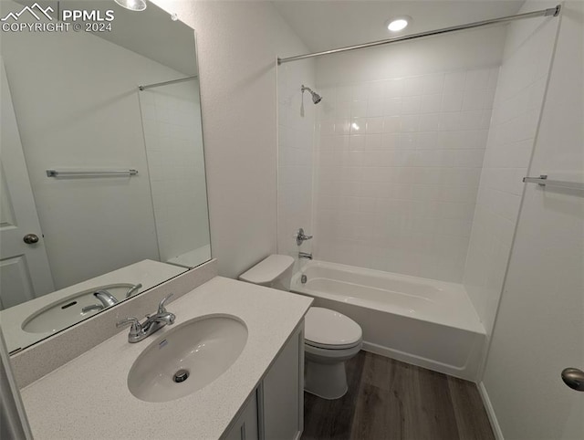 full bathroom with hardwood / wood-style floors, vanity, tiled shower / bath combo, and toilet