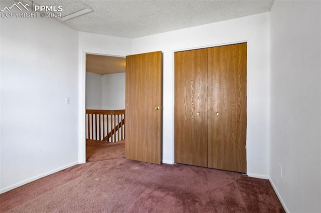 unfurnished bedroom with a textured ceiling, a closet, and dark colored carpet