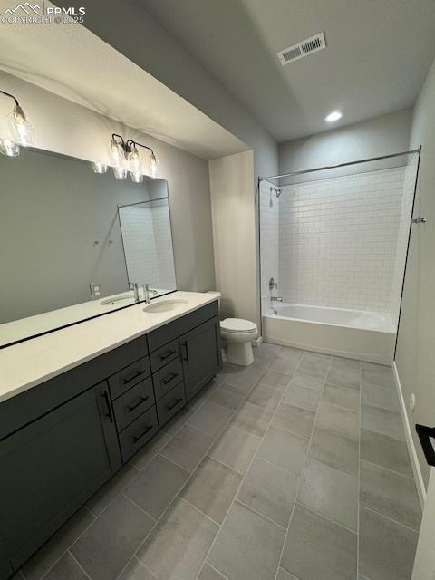 full bathroom featuring tiled shower / bath combo, toilet, and vanity