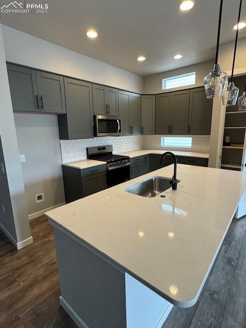 kitchen featuring dark hardwood / wood-style floors, stainless steel appliances, hanging light fixtures, and sink