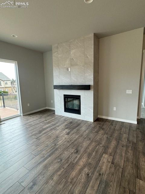 unfurnished living room with a tiled fireplace and hardwood / wood-style floors