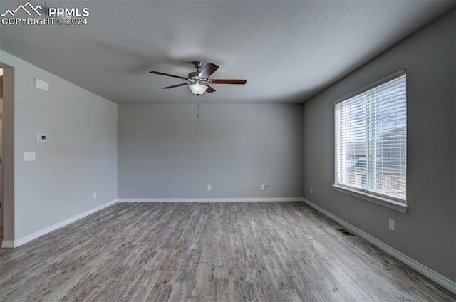 empty room featuring light wood-type flooring, a textured ceiling, and ceiling fan