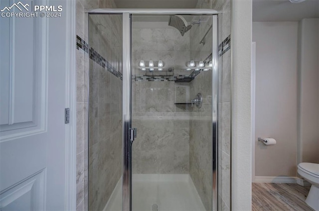 bathroom with hardwood / wood-style flooring, toilet, and an enclosed shower