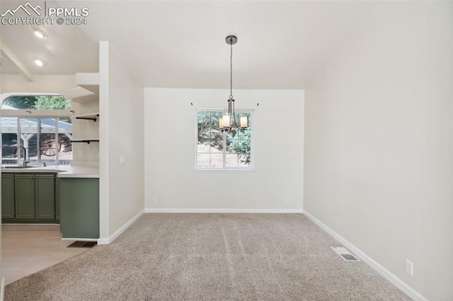 unfurnished dining area featuring sink, light carpet, and a chandelier